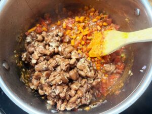 Cooked pinto beans added to a soup pot.