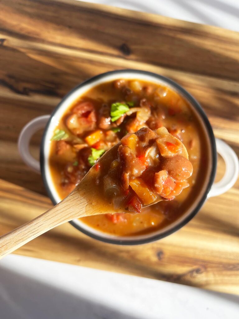 Overhead focus. A small wood spoon lifts some Mexican Pinto Bean Soup out of a full bowl.