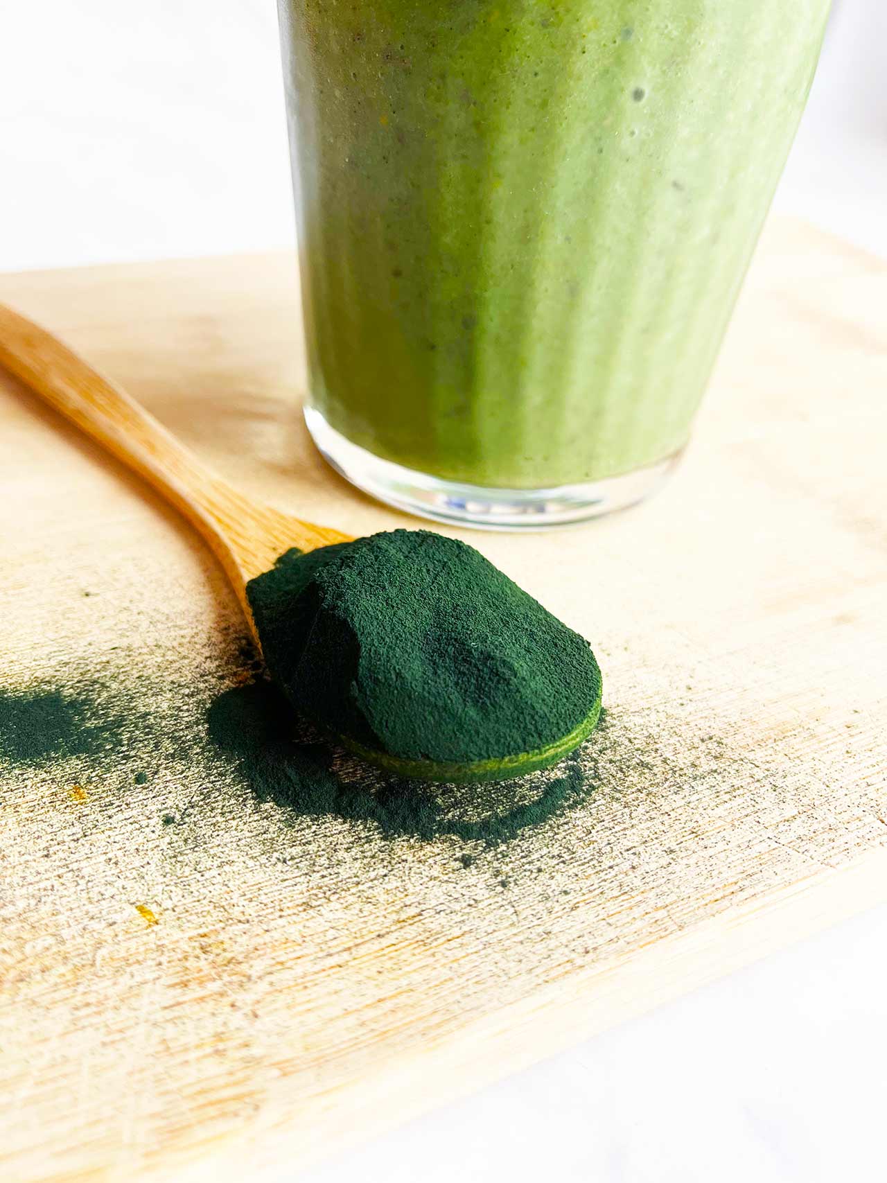 Closeup of a wood spoon holding a scoop of spirulina powder.