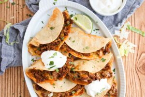 Over head partial view. An oval platter filled with Baked Beef Tacos.