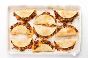 Overhead focus. A baking sheet with just-baked Beef Tacos.