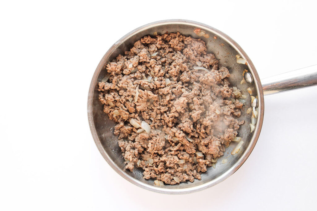 Cooked ground beef and onions in a skillet.