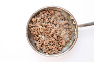 Cooked ground beef and onions in a skillet.