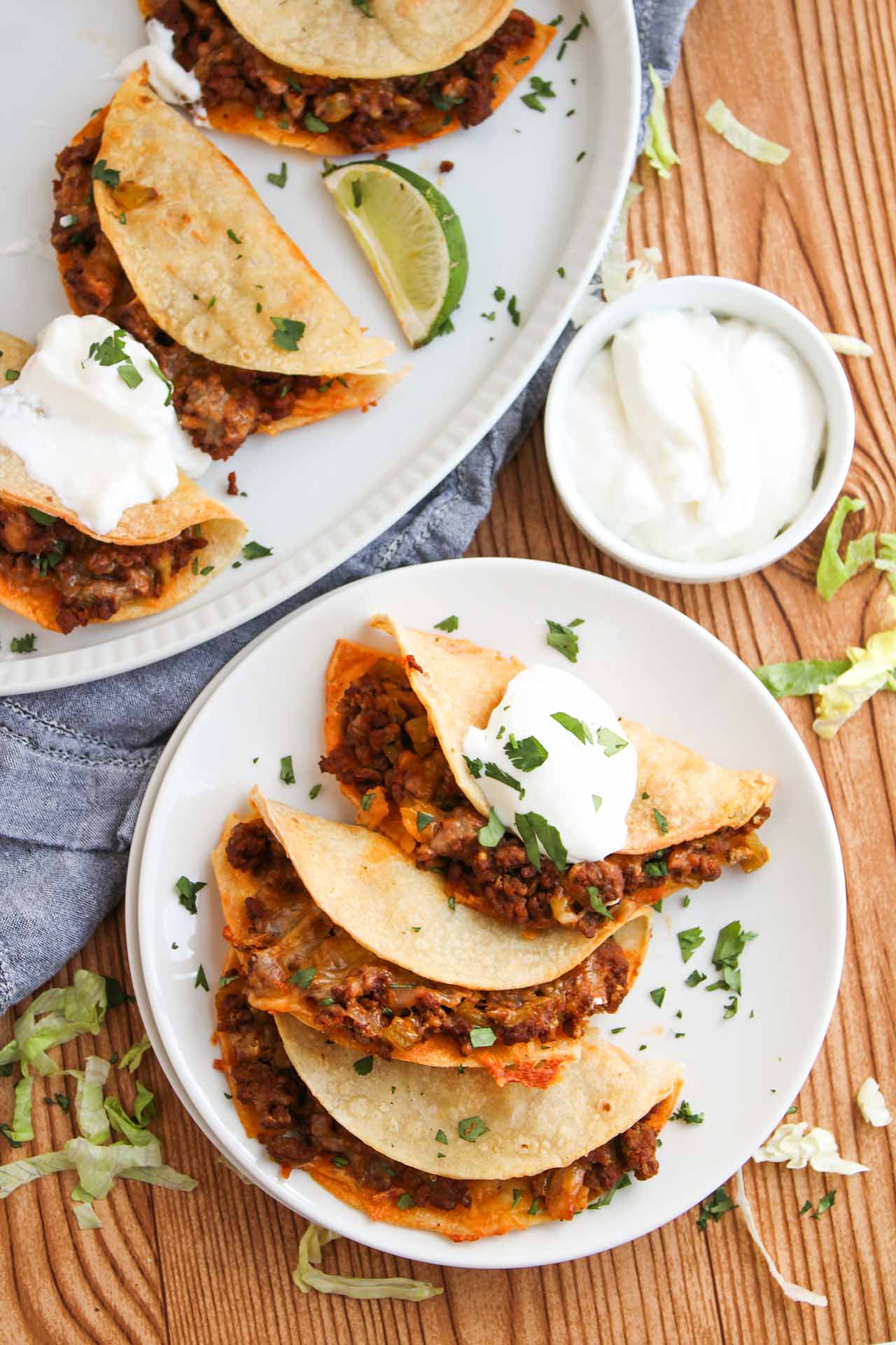 Overhead focus. A white plate with three Baked Beef Tacos, sitting next to a serving platter of the same.