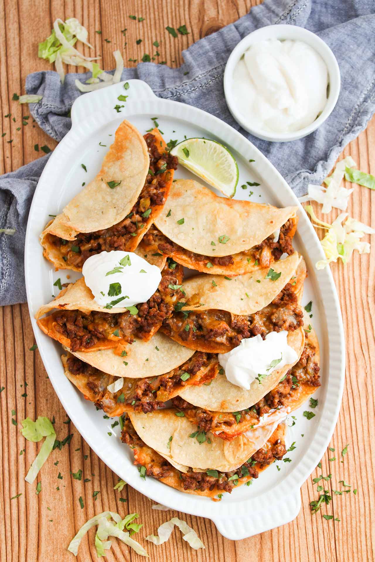 Overhead focus. An oval, white platter filled with Baked Beef Tacos.
