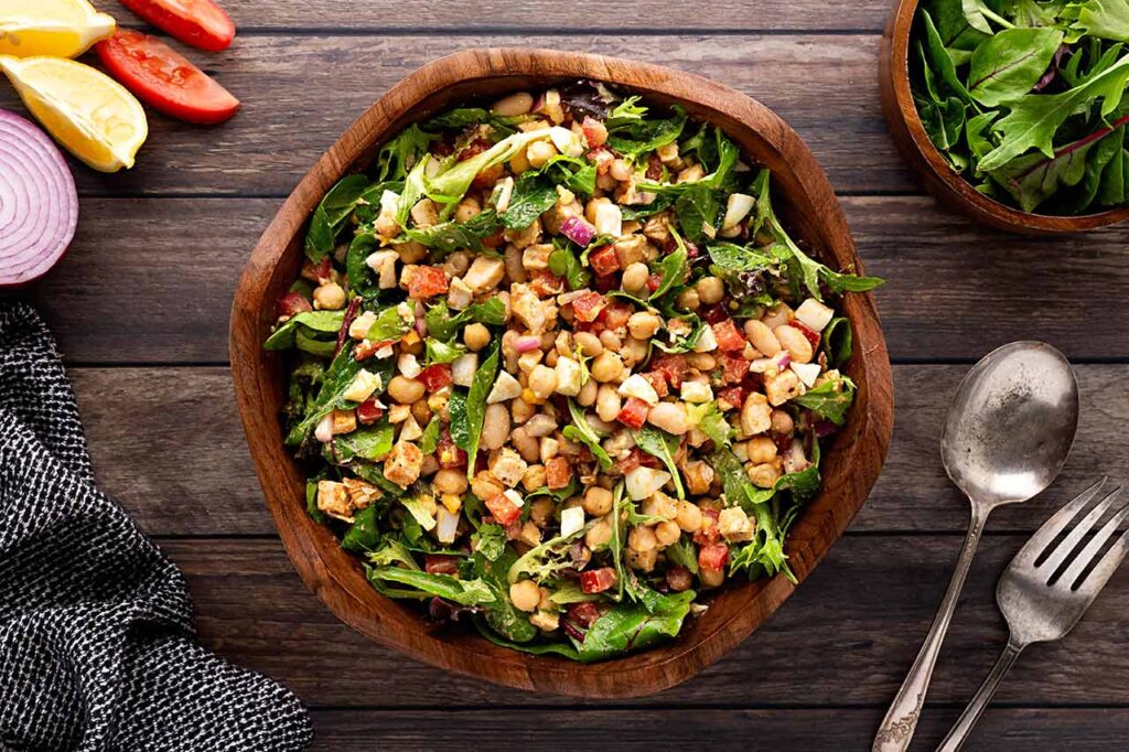 Overhead focus. A wood bowl filled with High Protein Dense Bean Salad.
