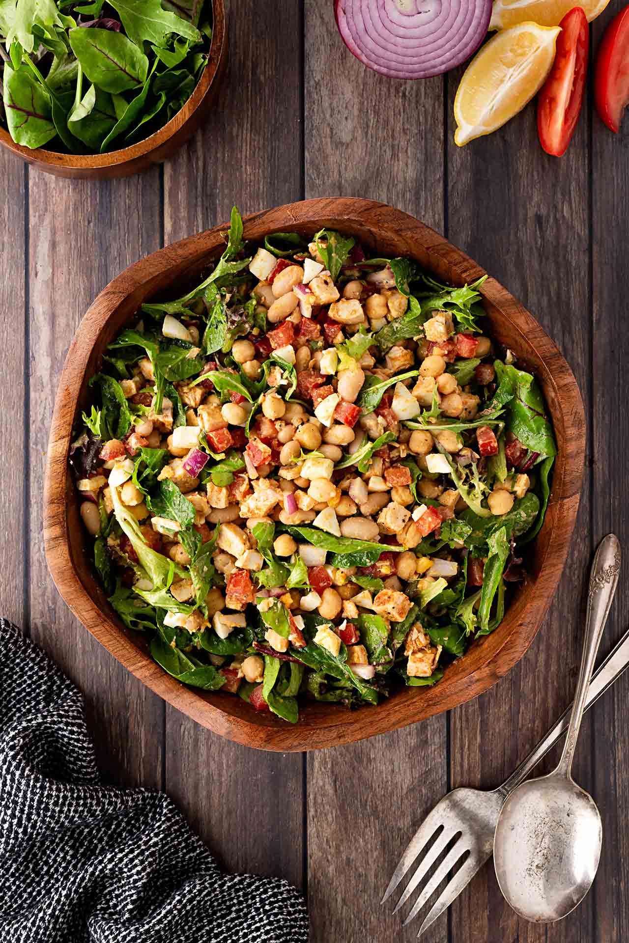 Overhead focus. High Protein Dense Bean Salad in a wood bowl on a wood surface.