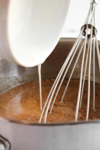 Pouring the starch slurry into the teriyaki sauce.