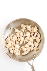 Cooked chicken chunks in a skillet.