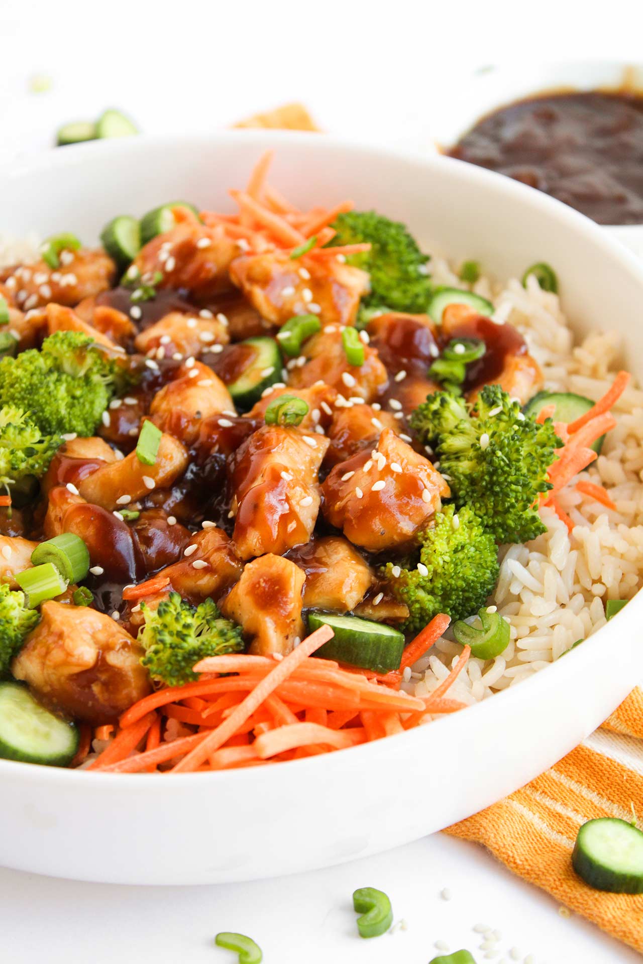 Partial front view of a Teriyaki chicken bowl in a white bowl on a table.