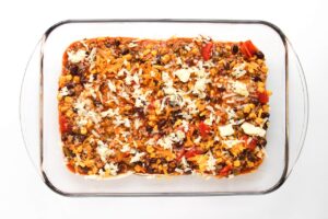 Beef Enchilada Casserole filling ladled over tortillas in a casserole dish.