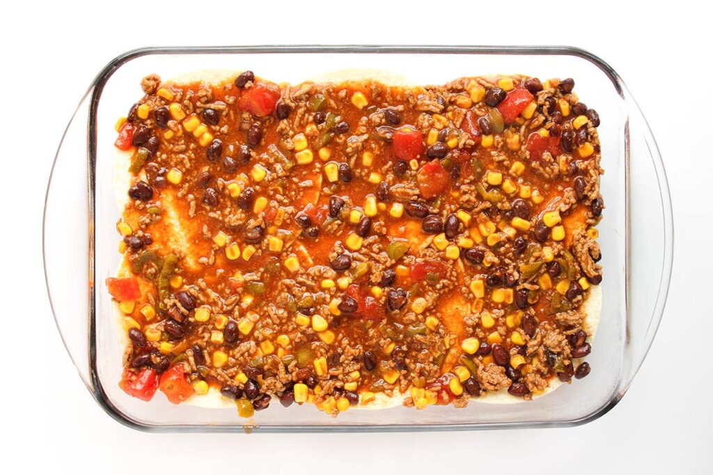 A second layer of tortillas and filling in a casserole dish.
