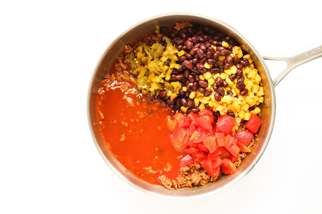 Remaining Beef Enchilada Casserole ingredients added to cooked ground beef in a skillet.