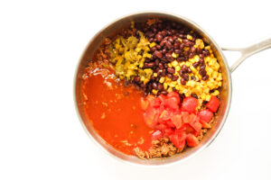 Remaining Beef Enchilada Casserole ingredients added to cooked ground beef in a skillet.