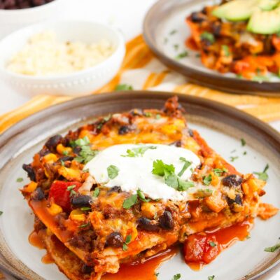 A cut slice of Beef Enchilada Casserole on a round, ceramic plate.