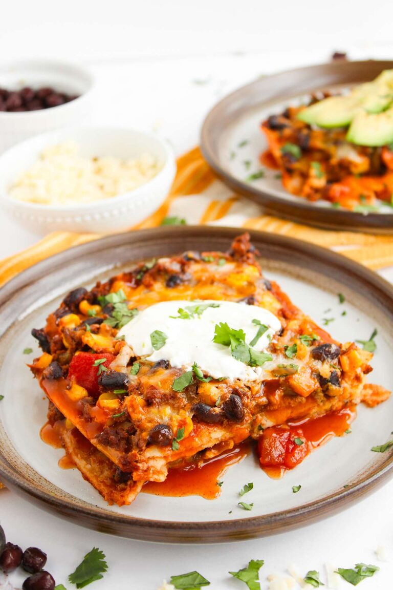 A cut slice of Beef Enchilada Casserole on a round, ceramic plate.