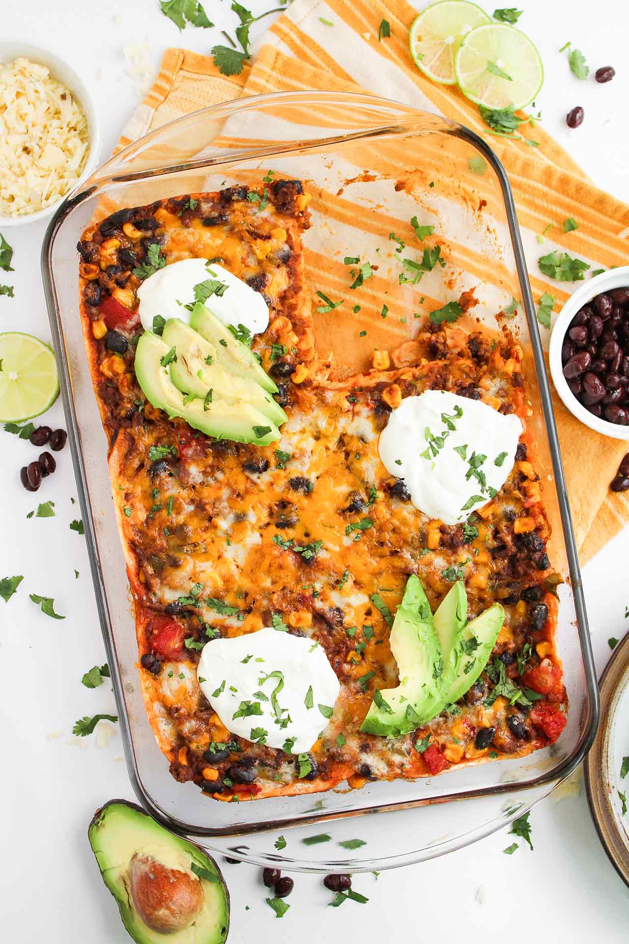 Overhead focus. A casserole dish of Beef Enchilada Casserole with one serving removed.